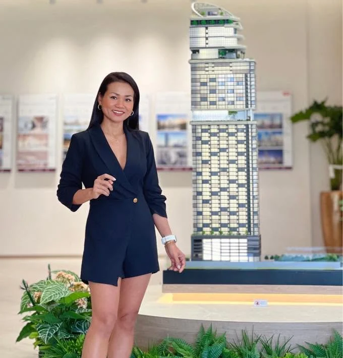 Sirinya beside a project tower model in a sales gallery